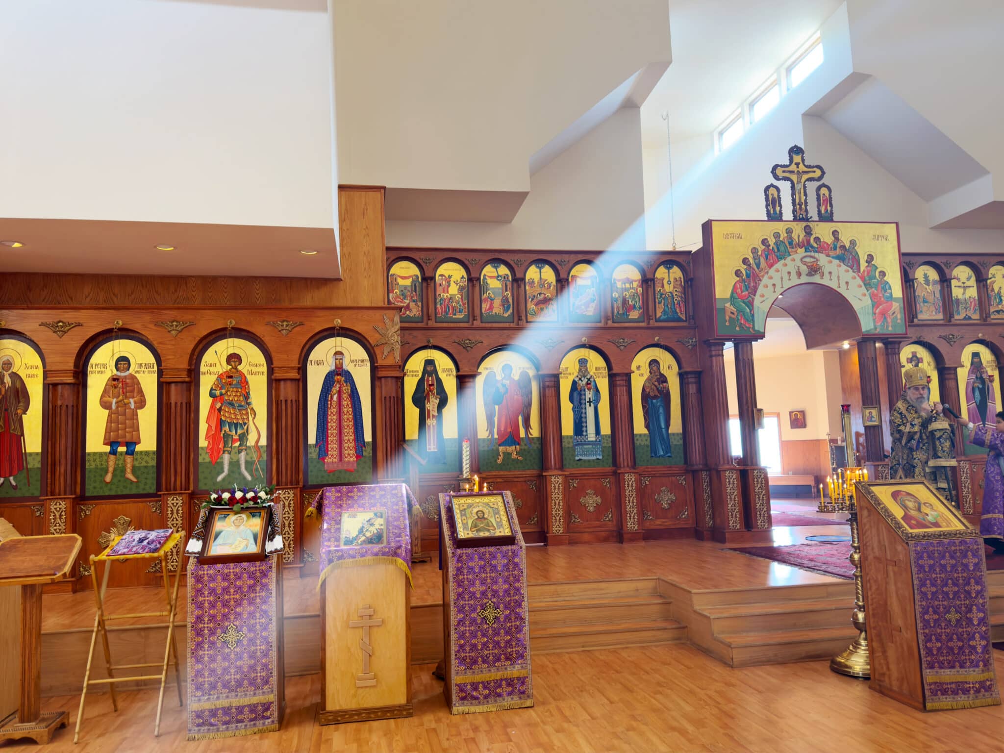 Interior of an Orthodox church with sunlight streaming through the windows, illuminating religious icons on the iconostasis